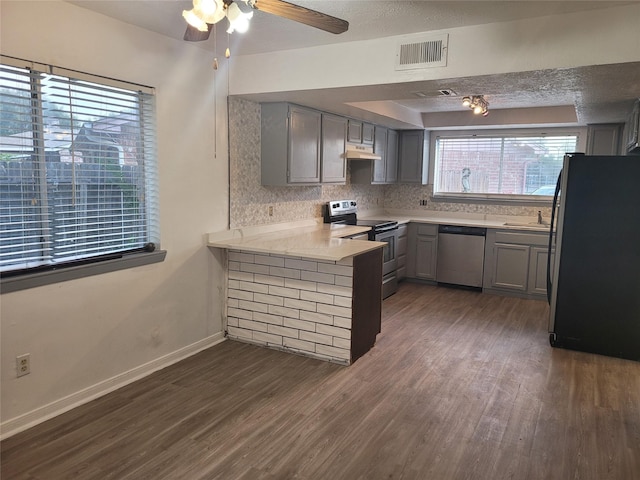 13930 New Village Ln, Sugar Land, TX 77498 - kitchen with appliances with stainless steel finishes, gray cabinets, dark wood-style floors, a peninsula, and light countertops