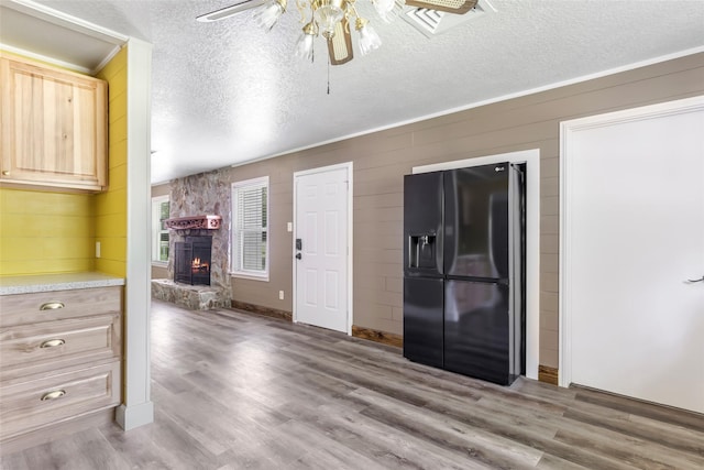 456 Cheatham Rd, Huffman, TX 77336 - kitchen featuring black fridge with ice dispenser, a ceiling fan, a textured ceiling, light brown cabinets, and a fireplace