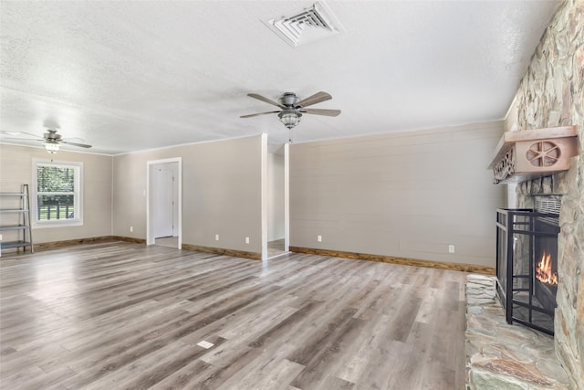 456 Cheatham Rd, Huffman, TX 77336 - unfurnished living room featuring a ceiling fan, a textured ceiling, wood finished floors, and a stone fireplace