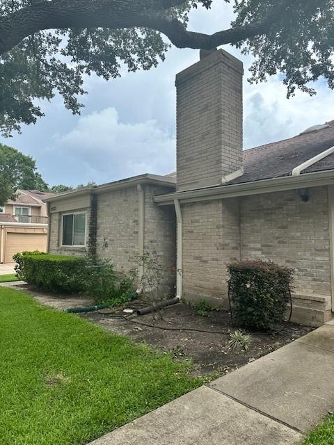 11522 Village Place Dr Unit 81, Houston, TX 77077 - view of home's exterior with a chimney, brick siding, and a yard