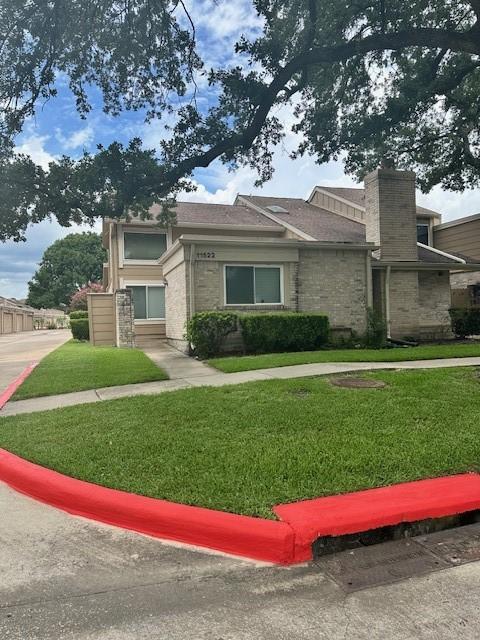 11522 Village Place Dr Unit 81, Houston, TX 77077 - view of front of house with a front lawn, stone siding, and a chimney