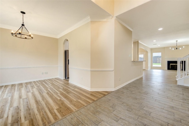 4202 Maurice Way, Stafford, TX 77477 - spare room featuring arched walkways, light wood-style flooring, ornamental molding, a chandelier, and a fireplace