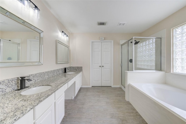 4202 Maurice Way, Stafford, TX 77477 - full bathroom with a shower stall, double vanity, a garden tub, and wood finished floors