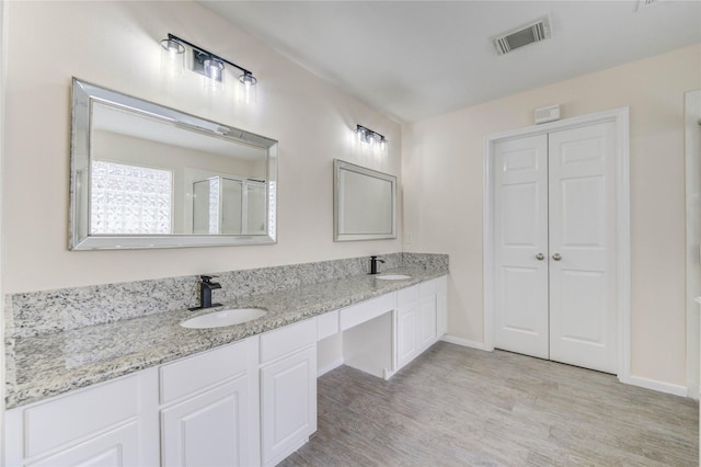 4202 Maurice Way, Stafford, TX 77477 - bathroom featuring wood finished floors, double vanity, and a shower with shower door