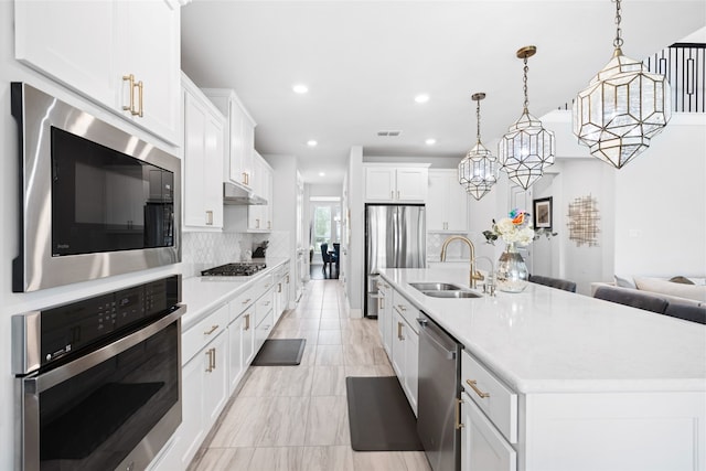 4710 Pecos Ridge Ln, Sugar Land, TX 77479 - kitchen with stainless steel appliances, under cabinet range hood, tasteful backsplash, light countertops, and a center island with sink