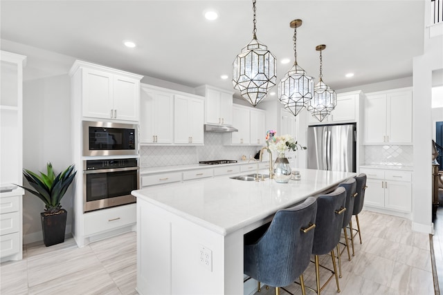 4710 Pecos Ridge Ln, Sugar Land, TX 77479 - kitchen featuring stainless steel appliances, recessed lighting, backsplash, light countertops, and a center island with sink
