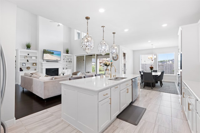 4710 Pecos Ridge Ln, Sugar Land, TX 77479 - kitchen with appliances with stainless steel finishes, a chandelier, light countertops, a fireplace, and white cabinetry