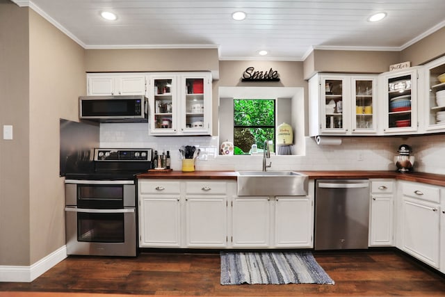 221 Kings Way, Coldspring, TX 77331 - kitchen featuring appliances with stainless steel finishes, butcher block counters, white cabinetry, tasteful backsplash, and ornamental molding