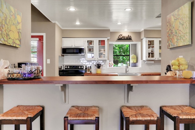 221 Kings Way, Coldspring, TX 77331 - kitchen featuring stainless steel microwave, range, wooden counters, backsplash, and crown molding
