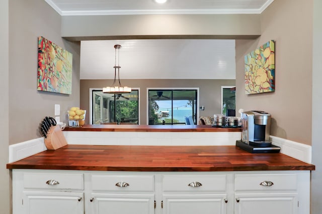 221 Kings Way, Coldspring, TX 77331 - kitchen with wooden counters, white cabinetry, a chandelier, ornamental molding, and pendant lighting