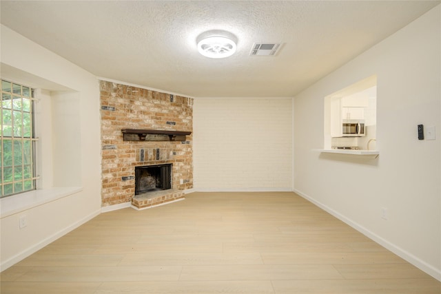 12803 High Star Dr, Houston, TX 77072 - unfurnished living room with a textured ceiling, light wood-style floors, and a brick fireplace