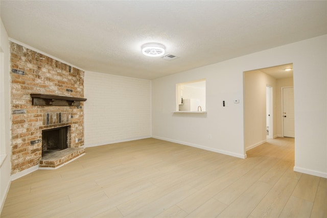 12803 High Star Dr, Houston, TX 77072 - unfurnished living room with wood finished floors, a textured ceiling, and a brick fireplace