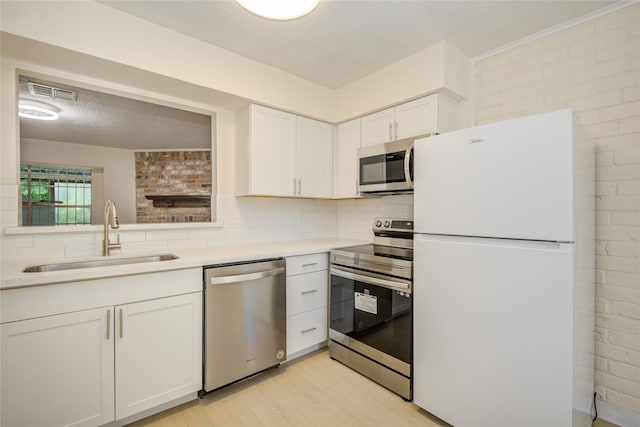 12803 High Star Dr, Houston, TX 77072 - kitchen featuring appliances with stainless steel finishes, decorative backsplash, white cabinetry, light countertops, and light wood-style floors