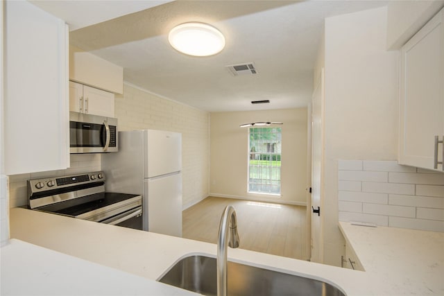 12803 High Star Dr, Houston, TX 77072 - kitchen with appliances with stainless steel finishes, tasteful backsplash, white cabinets, and light wood finished floors