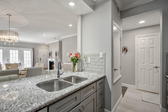 248 Wilcrest Dr Unit 248, Houston, TX 77042 - kitchen with crown molding, gray cabinetry, light stone counters, a chandelier, and pendant lighting
