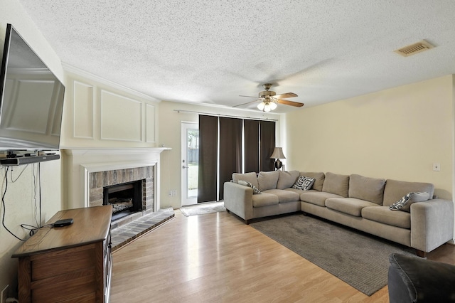 10410 Dude Rd, Houston, TX 77064 - living room featuring ceiling fan, light wood-style floors, a fireplace, and a textured ceiling