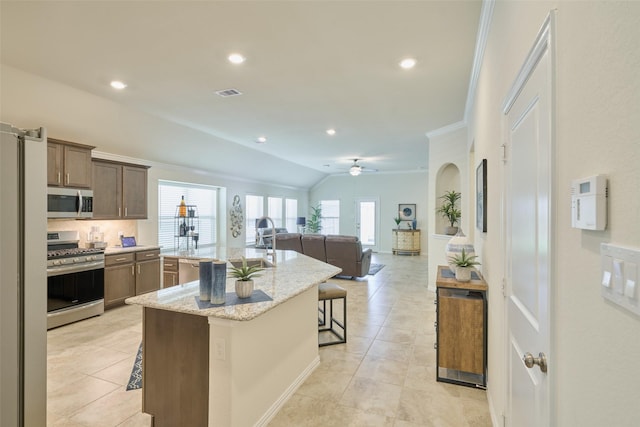 18811 Palmetto Hills Dr, New Caney, TX 77357 - kitchen featuring appliances with stainless steel finishes, a kitchen breakfast bar, an island with sink, decorative backsplash, and crown molding