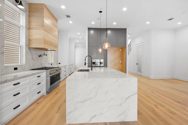 1520 Nicholson St, Houston, TX 77008 - kitchen featuring stainless steel range, light wood-style flooring, backsplash, light stone counters, and recessed lighting
