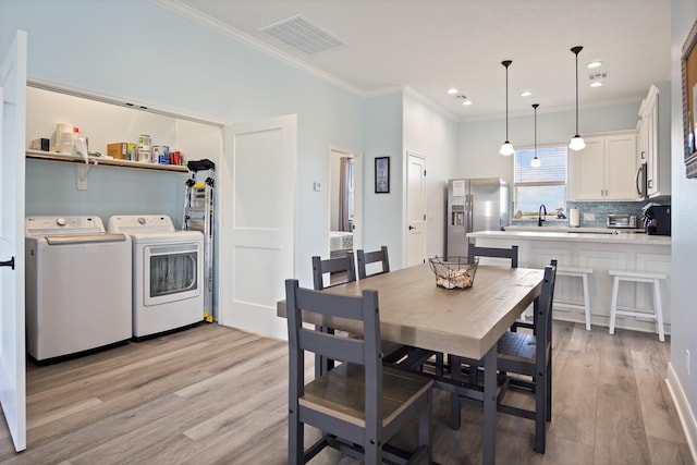 1229 N Stingaree Dr, Crystal Beach, TX 77650 - dining area featuring separate washer and dryer, ornamental molding, light wood-style floors, and recessed lighting