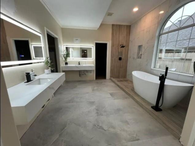 20522 Riverside Pines Dr, Houston, TX 77346 - bathroom with a freestanding tub, two vanities, ornamental molding, a tile shower, and tile walls