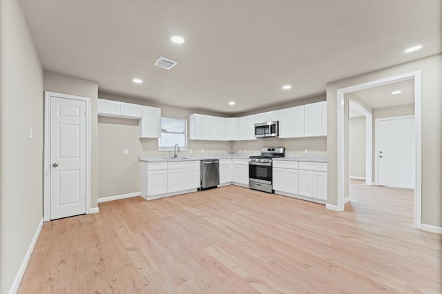 3626 Sparrow St, Houston, TX 77051 - kitchen featuring appliances with stainless steel finishes, light wood-type flooring, white cabinets, and recessed lighting