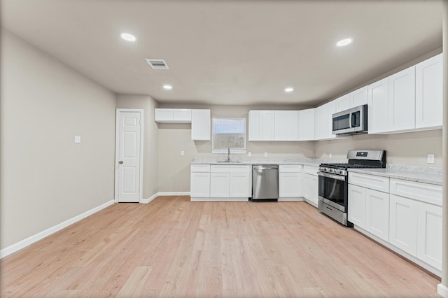 3626 Sparrow St, Houston, TX 77051 - kitchen with appliances with stainless steel finishes, light wood finished floors, white cabinetry, recessed lighting, and light stone countertops