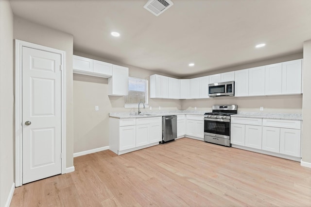 3626 Sparrow St, Houston, TX 77051 - kitchen featuring stainless steel appliances, light wood finished floors, white cabinetry, recessed lighting, and light stone counters