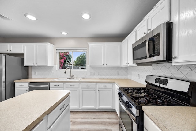 21002 Pineda Cir, Richmond, TX 77406 - kitchen featuring stainless steel appliances, light countertops, white cabinetry, light wood-type flooring, and tasteful backsplash