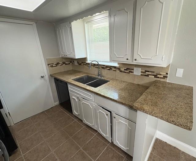 12127 Rhinebeck Dr, Houston, TX 77089 - kitchen with tasteful backsplash, white cabinetry, black dishwasher, and dark tile patterned flooring