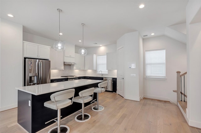 1740 Ojeman Point Ln, Houston, TX 77055 - kitchen featuring stainless steel appliances, a center island, a kitchen breakfast bar, white cabinets, and decorative backsplash