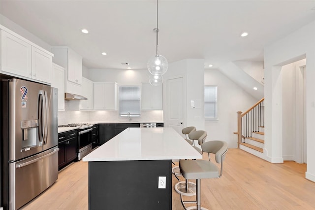 1740 Ojeman Point Ln, Houston, TX 77055 - kitchen featuring appliances with stainless steel finishes, a kitchen breakfast bar, light wood finished floors, decorative backsplash, and light countertops