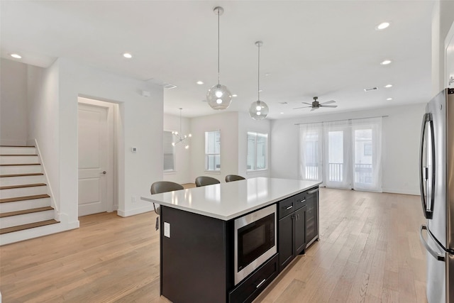 1740 Ojeman Point Ln, Houston, TX 77055 - kitchen featuring appliances with stainless steel finishes, light wood-type flooring, light countertops, recessed lighting, and a breakfast bar area