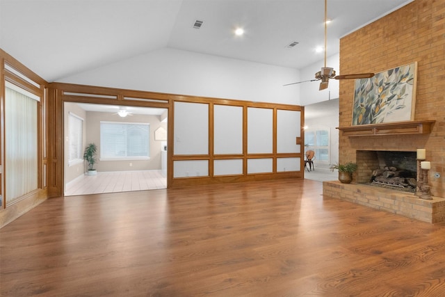 116 April Wind Dr E, Montgomery, TX 77356 - unfurnished living room featuring a ceiling fan, a brick fireplace, wood finished floors, and high vaulted ceiling