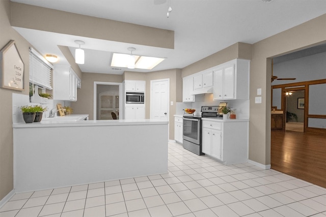 116 April Wind Dr E, Montgomery, TX 77356 - kitchen with stainless steel appliances, a peninsula, under cabinet range hood, light countertops, and white cabinetry