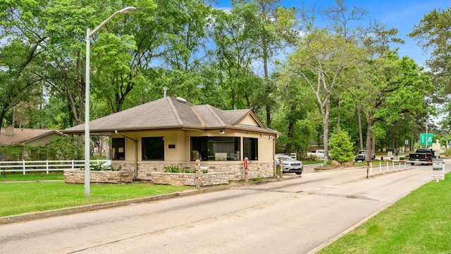 17 Lakeview Vlg, Montgomery, TX 77356 - view of front facade featuring stone siding, stucco siding, a shingled roof, and view of scattered trees