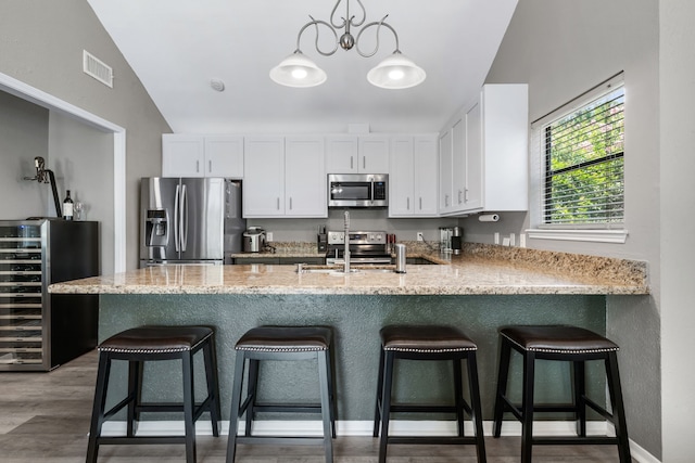 17 Lakeview Vlg, Montgomery, TX 77356 - kitchen featuring stainless steel appliances, wine cooler, white cabinetry, light stone countertops, and light wood-style flooring