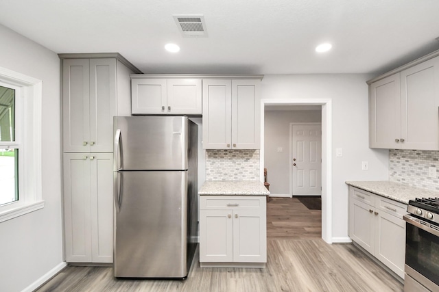 3603 Idaho St, Houston, TX 77021 - kitchen featuring stainless steel appliances, light wood-style flooring, decorative backsplash, light stone counters, and recessed lighting
