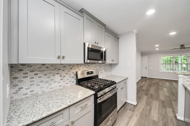 3603 Idaho St, Houston, TX 77021 - kitchen featuring stainless steel appliances, light wood-type flooring, backsplash, recessed lighting, and light stone counters