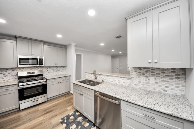 3603 Idaho St, Houston, TX 77021 - kitchen with appliances with stainless steel finishes, gray cabinets, ornamental molding, backsplash, and light wood-style floors