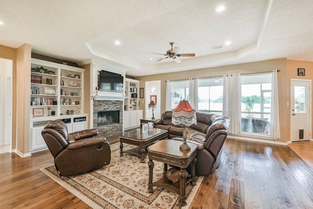 29218 Hay Meadow Ct, Waller, TX 77484 - living area featuring a tray ceiling, wood-type flooring, ceiling fan, a fireplace, and recessed lighting