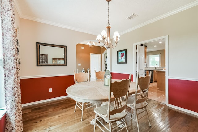 29218 Hay Meadow Ct, Waller, TX 77484 - dining room featuring light wood-type flooring, ornamental molding, arched walkways, and a chandelier