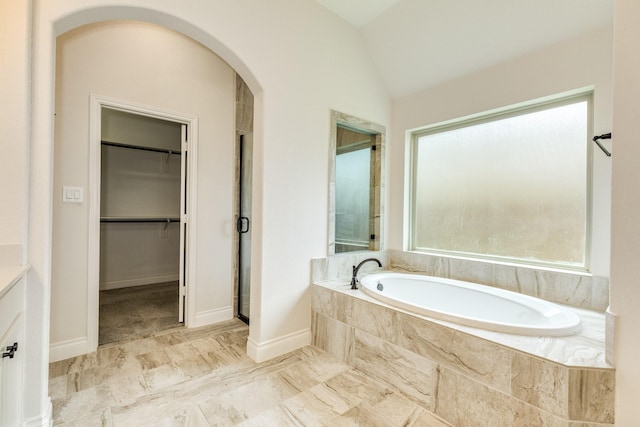 10318 Granite Ct, Iowa Colony, TX 77583 - bathroom featuring healthy amount of natural light, a bath, marble look tile flooring, a spacious closet, and lofted ceiling
