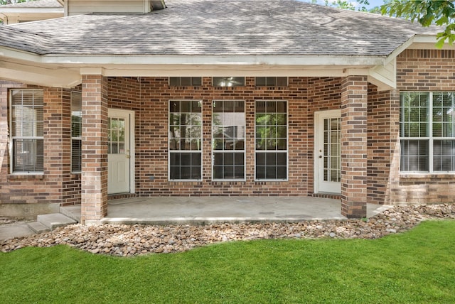 53 Silver Crescent Ct, The Woodlands, TX 77382 - doorway to property with a shingled roof, brick siding, and a patio area