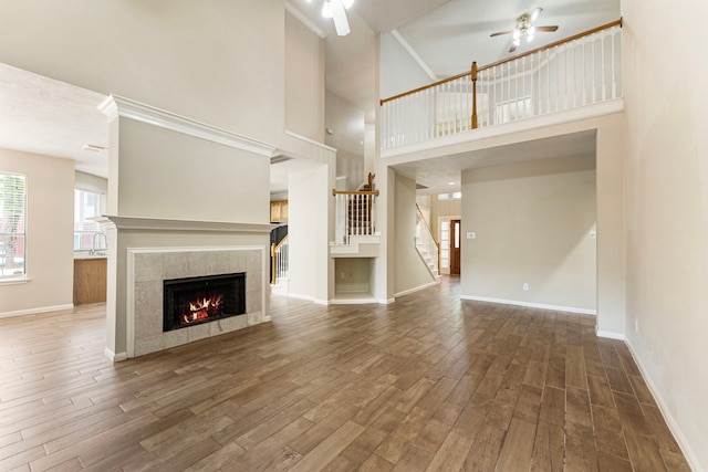 53 Silver Crescent Ct, The Woodlands, TX 77382 - unfurnished living room featuring ceiling fan, a fireplace, wood finished floors, stairs, and a high ceiling
