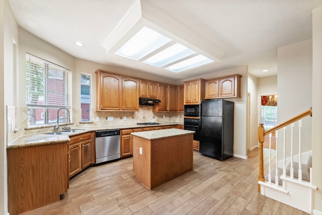 53 Silver Crescent Ct, The Woodlands, TX 77382 - kitchen featuring black appliances, under cabinet range hood, decorative backsplash, light stone counters, and a kitchen island