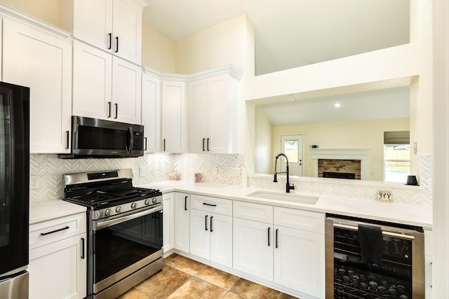 21 Alexander Ct, Angleton, TX 77515 - kitchen featuring stainless steel gas range oven, wine cooler, black refrigerator, light countertops, and tasteful backsplash