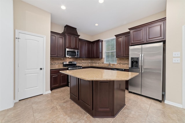 9 Cheswood Manor Dr, Spring, TX 77382 - kitchen featuring appliances with stainless steel finishes, dark brown cabinets, decorative backsplash, a kitchen island, and light tile patterned flooring