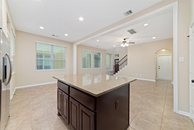 9 Cheswood Manor Dr, Spring, TX 77382 - kitchen featuring a kitchen island, dark brown cabinetry, light tile patterned flooring, light stone countertops, and a ceiling fan