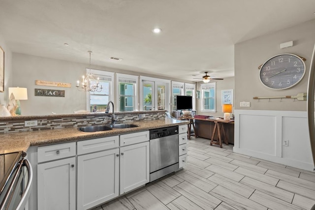 4121 Pointe W Dr Unit 103, Galveston, TX 77554 - kitchen with stainless steel appliances, white cabinets, a chandelier, ceiling fan, and wainscoting