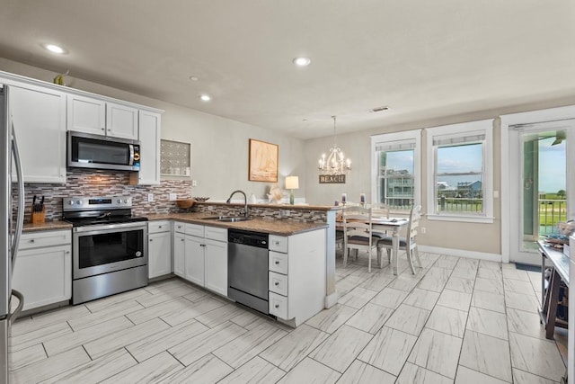4121 Pointe W Dr Unit 103, Galveston, TX 77554 - kitchen featuring appliances with stainless steel finishes, a peninsula, decorative backsplash, healthy amount of natural light, and recessed lighting